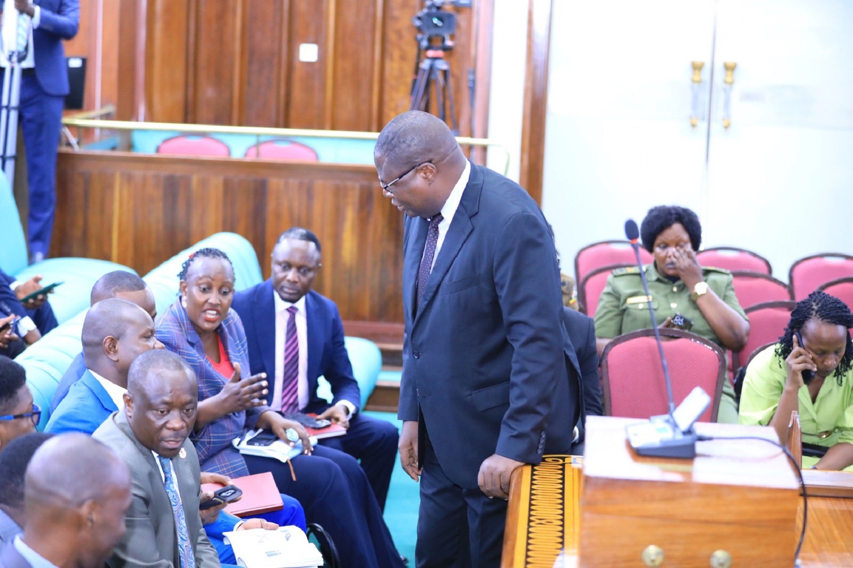 Defence minister, Hon. Jacob Oboth (standing) engaging with Members of the Opposition before commencement of the session
